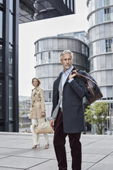 Germany, Duesseldorf, two fashionable business people with traveling bags - RORF01532