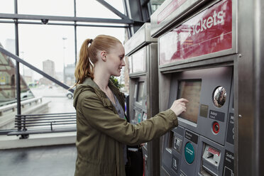 Seitenansicht einer Frau, die einen Fahrkartenautomaten am Bahnhof benutzt - MASF08611
