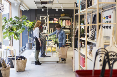Besitzerin hilft Frau beim Kauf eines Schals in einer Boutique - MASF08621