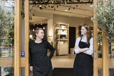 Smiling female owners standing at doorway of store - MASF08630