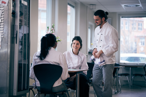Männliche und weibliche Köche besprechen die Speisekarte in einem Restaurant, lizenzfreies Stockfoto