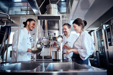 Lächelnde männliche und weibliche Köche beim Kochen in einer Großküche - MASF08673