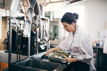 Mid adult female chef preparing food in commercial kitchen - MASF08703