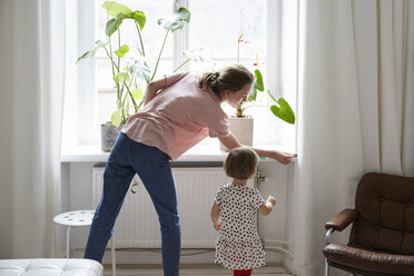 Tochter schaut auf ein Designer-Messfenster zu Hause - MASF08757