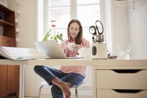 Full length of young woman examining financial bill while working from home stock photo