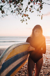 Ältere Frau mit Surfbrett am Strand bei Sonnenuntergang - MASF08781