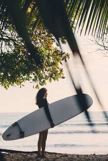 Full length side view of mature woman carrying surfboard at beach - MASF08788