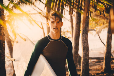 Porträt eines selbstbewussten jungen Mannes mit Surfbrett am Strand - MASF08797