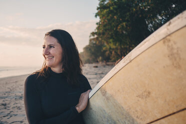 Lächelnde reife Frau mit Surfbrett am Strand - MASF08804