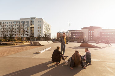 Teenager-Mädchen steht und spricht mit Freunden in einem Skateboard-Park in der Stadt - MASF08817