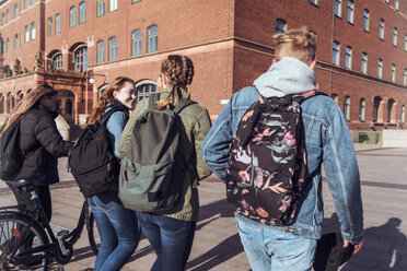 Rückansicht von Teenager-Freunden, die gemeinsam auf einem Fußweg in der Stadt spazieren gehen - MASF08837