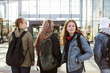 Porträt eines Mädchens im Teenageralter mit Freunden vor einem Bahnhof in der Stadt - MASF08847