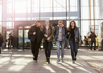 Full length of happy friends walking against railroad station in city - MASF08852