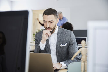 Serious businessman using laptop at desk in office - MASF08902