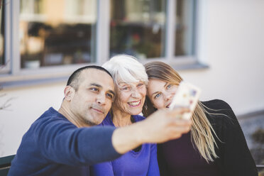 Mehrgenerationenfamilie lächelt bei einem Selfie vor einem Pflegeheim - MASF08906