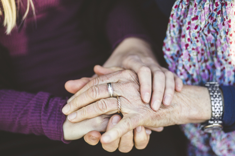 Ausgeschnittenes Bild von Enkelin und Großmutter, die sich an den Händen halten, lizenzfreies Stockfoto