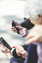 Cropped image of senior couple using mobile phone while sitting outdoors - MASF08937