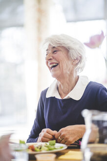 Fröhliche ältere Frau beim Mittagessen am Tisch im Pflegeheim - MASF08949