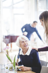 Ältere Frau im Gespräch mit ihrer Enkelin bei einer Mahlzeit am Tisch im Pflegeheim - MASF08958