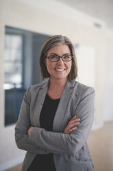 Portrait of confident mature businesswoman standing with arms crossed in office - MASF08973