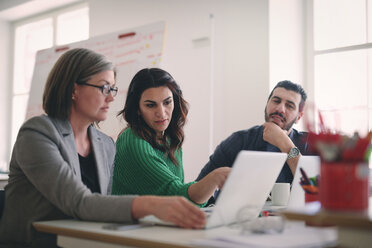 Creative business people discussing over laptop at desk in office - MASF08976