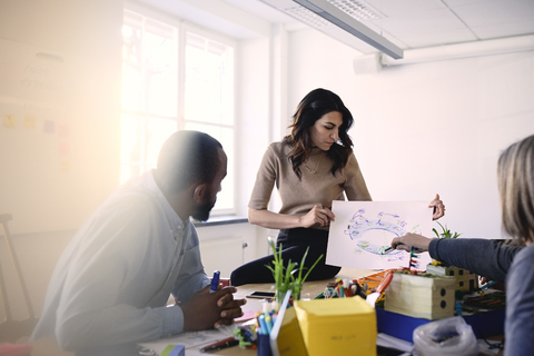 Männliche und weibliche Ingenieure diskutieren über ein Diagramm am Tisch während einer Besprechung im Büro, lizenzfreies Stockfoto