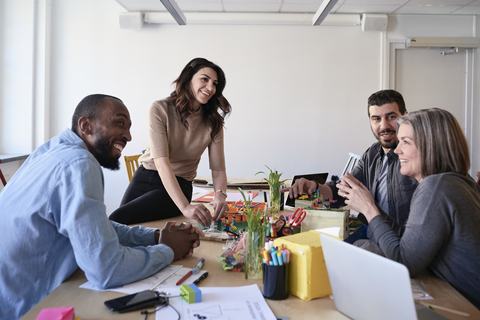 Multi-ethnische Ingenieure lächelnd bei der Arbeit an einem Projekt am Tisch im Büro, lizenzfreies Stockfoto