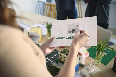 Cropped image of female engineer holding diagrams at table in office - MASF09009