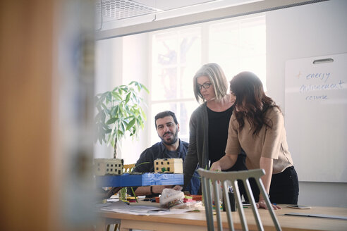 Multi-ethnische männliche und weibliche Ingenieure diskutieren über ein architektonisches Modell am Tisch während einer Besprechung im Büro - MASF09017