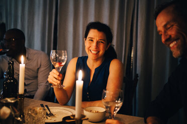 Happy woman enjoying dinner with male friends in party at home - MASF09034