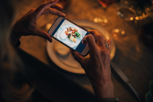 Hohe Winkel Ansicht der reifen Frau fotografiert Essen am Esstisch in Dinner Party - MASF09036