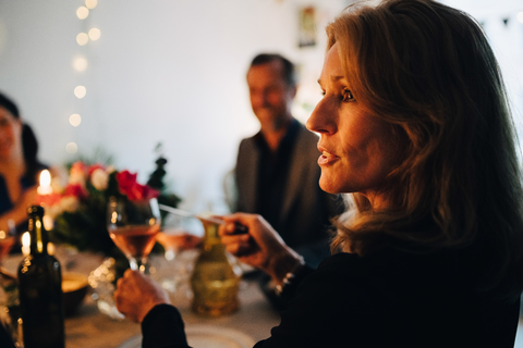 Close-up of woman raising toast with wineglass during dinner party stock photo