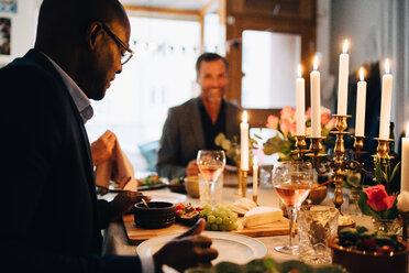 Mature man having dinner with friends at dining table in dinner party - MASF09046