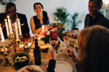 Frau stößt mit einem Weinglas bei einer Dinnerparty zu Hause an - MASF09047