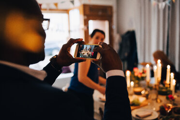 Mann fotografiert Freunde mit dem Smartphone auf einer Dinnerparty - MASF09053