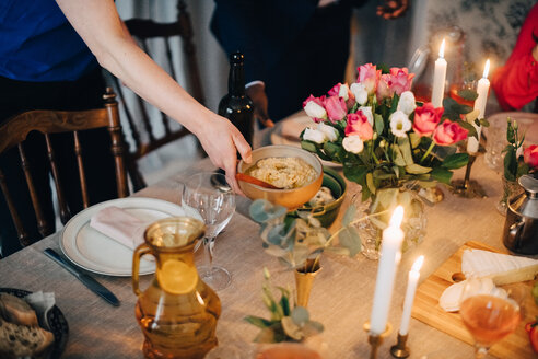 Abgeschnittene Hand einer Frau, die das Essen auf dem Esstisch bei einer Dinnerparty anrichtet - MASF09060