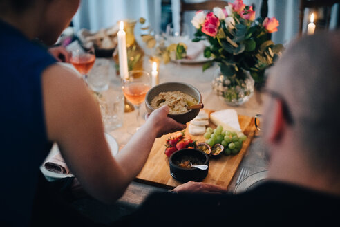 Frau serviert Essen an männlichen Mann am Esstisch in Dinner Party - MASF09061