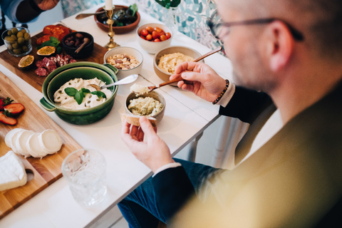 Hoher Blickwinkel des Mannes mit Essen am Tisch während einer Dinnerparty, lizenzfreies Stockfoto