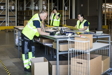 Multi-ethnic workers packing merchandise at distribution warehouse - MASF09125