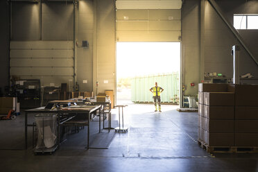 Full length of senior warehouse worker standing at storage room doorway - MASF09129