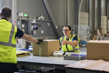 Coworkers packing merchandise on desk at warehouse - MASF09130