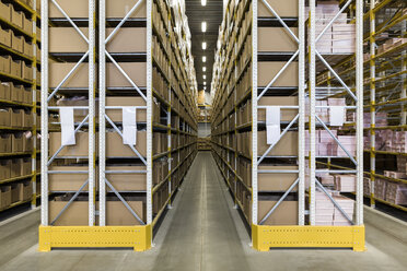 Empty narrow aisle amidst racks at distribution warehouse - MASF09183