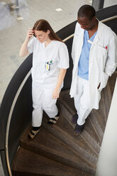 Blick von oben auf multiethnische Ärzte, die sich auf einer Wendeltreppe im Krankenhaus nach unten bewegen - MASF09193
