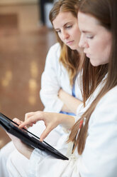 Selbstbewusste Ärztinnen diskutieren über ein digitales Tablet auf dem Flur eines Krankenhauses - MASF09199