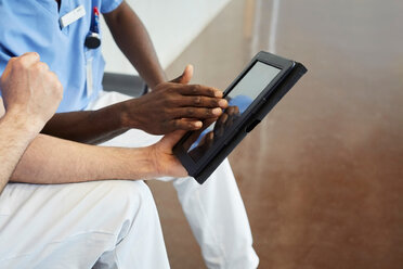 High angle view of male nurses discussing over digital tablet while sitting in corridor at hospital - MASF09201