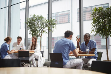 Ein multiethnisches medizinisches Team sitzt in der Cafeteria eines Krankenhauses - MASF09236