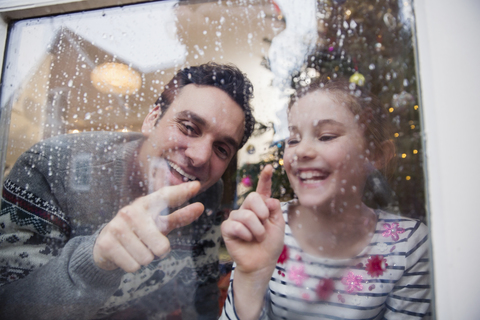 Father and daughter drawing in condensation on wet winter window stock photo