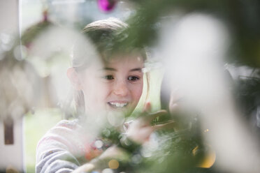 Smiling girl decorating Christmas tree - HOXF03776