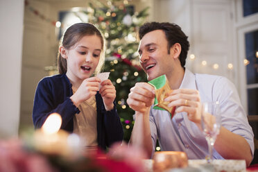 Vater und Tochter beim Öffnen von Weihnachtsgebäck beim Weihnachtsessen - HOXF03778