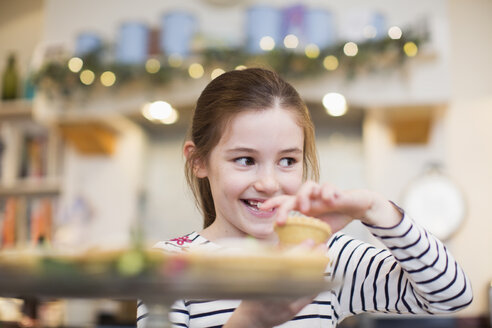 Lächelndes Mädchen isst Weihnachts-Cupcake - HOXF03784